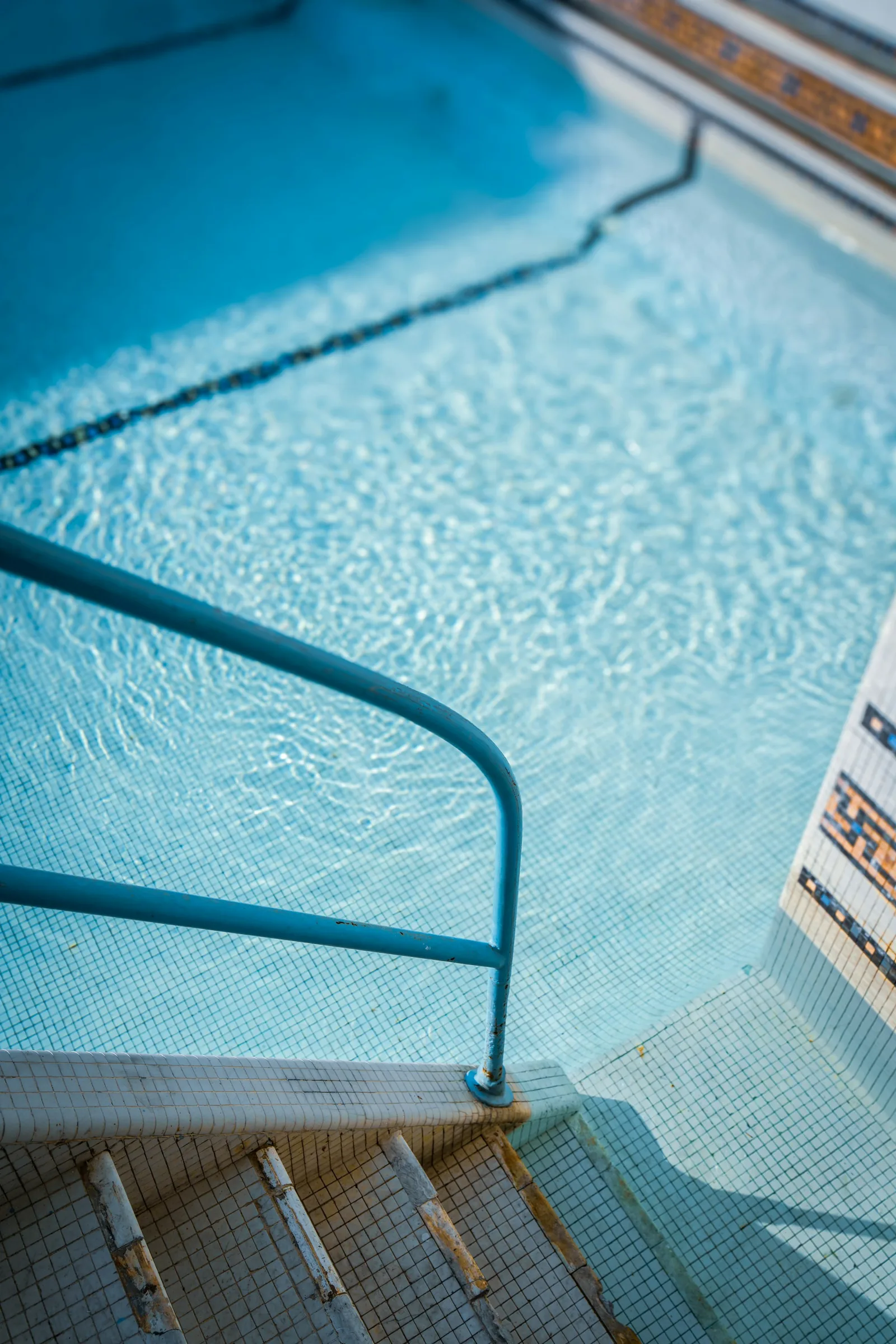 Entry steps in a blue mosaic-tiled swimming pool showing how tiles amplify blue colour